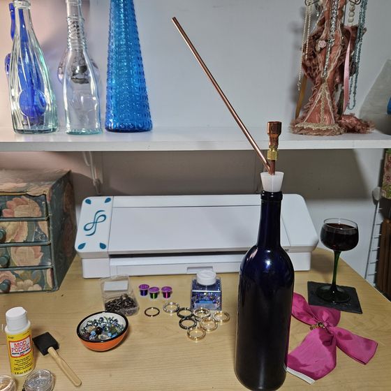 At the craft table mid-project, a glass of wine within reach.
